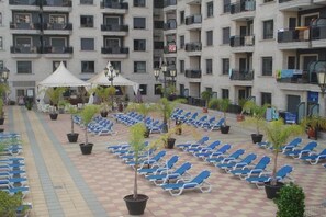 A courtyard with blue lounge chairs arranged in rows, surrounded by potted plants and a white canopy structure. - Apartamentos Nuriasol (Fuengirola)