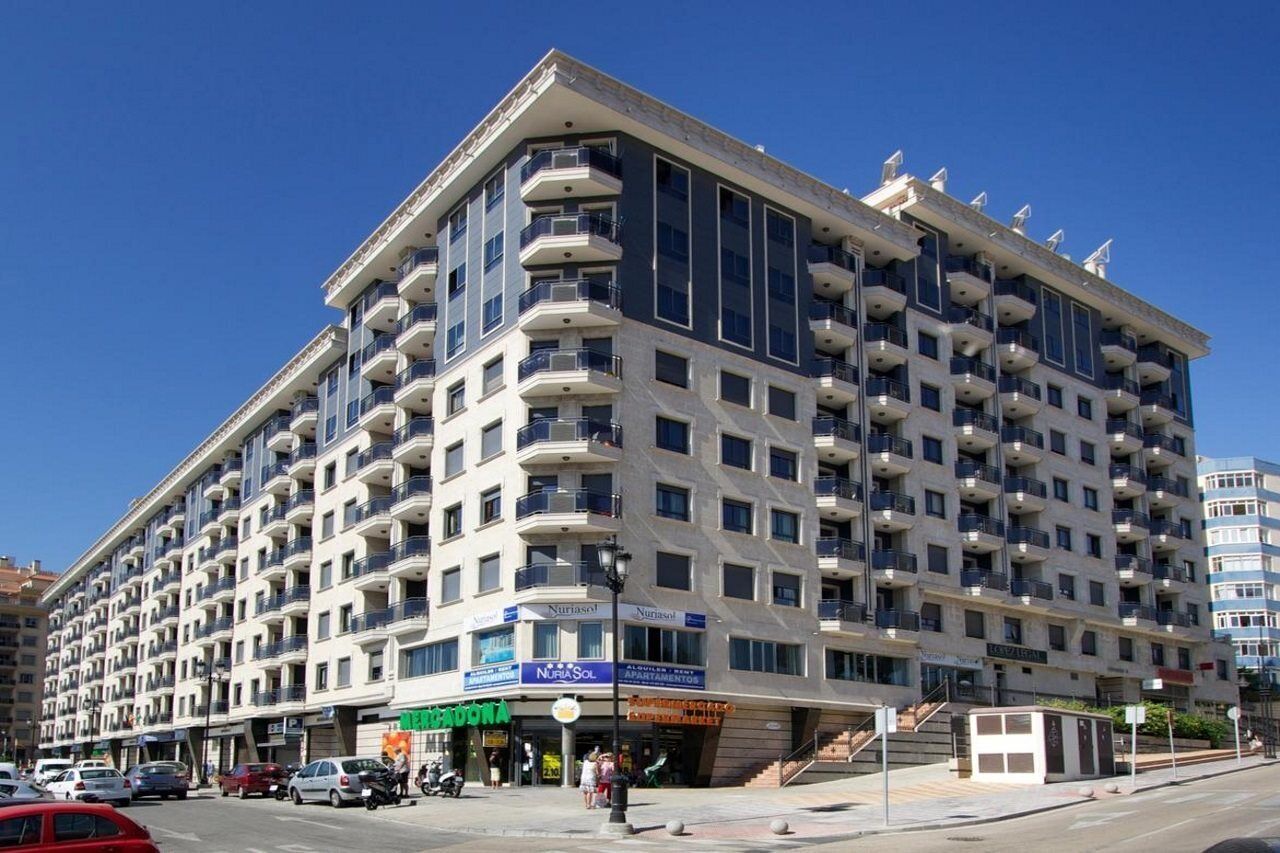 Een hotel met meerdere verdiepingen, balkons, een restaurant op de begane grond en een zichtbare ingang.