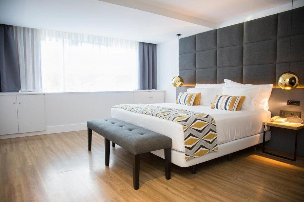 Un dormitorio moderno con una cama grande, un banco, una mesita de noche y un armario.