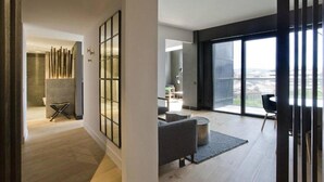 A modern living room with a large sliding glass door leading to a balcony, a seating area with a sofa and a coffee table, and a view of the cityscape. - Tres Reyes Pamplona (Pamplona)