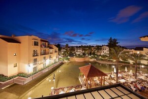 Un hotel con piscina, zona de estar exterior y vistas de los edificios circundantes.