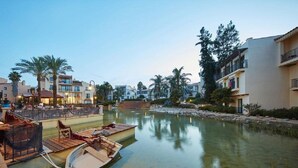Ein Hotel am Wasserufer mit einer Anlegestelle, Palmen und einem ruhigen Fluss.