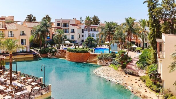 Ein Resort mit Swimmingpool, Palmen und mehreren Gebäuden.