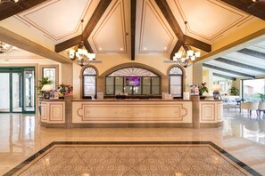 Eine großzügige Lobby mit einer Rezeption, Kronleuchtern und einem gemusterten Boden.