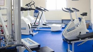 Une salle de sport équipée de divers appareils d’exercice, notamment des tapis de course et un banc de musculation.