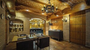 Un restaurant chaleureux avec des murs en briques, un plafond en bois et une salle à manger centrale dotée de tables et de chaises.