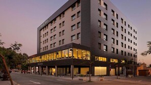 A modern hotel with a flat roof, multiple floors, and a ground-level restaurant. - Suittes Hotel (Algeciras)