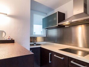 Una cocina moderna con campana extractora de acero inoxidable, horno empotrado y ventana sobre el fregadero.