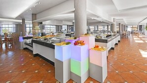 Eine großzügige Hotelhalle mit mehreren Speisebereichen, einer zentralen Säule und einem Fliesenboden.