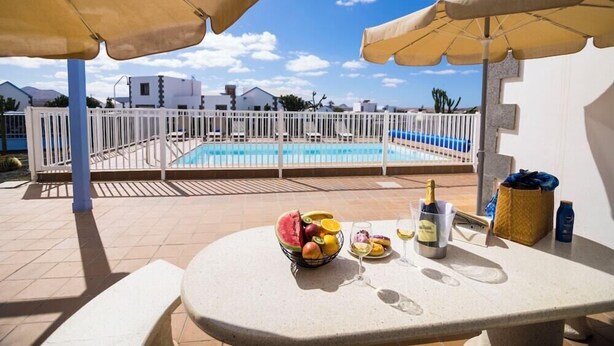 A terrace with a pool, outdoor seating, and umbrellas.