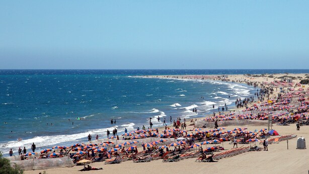 A beach with numerous umbrellas and sun loungers, indicating a popular tourist spot. - Montemar Apartments (San Bartolomé de Tirajana)