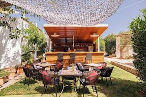An outdoor bar area with a wooden counter, wicker chairs, and a patterned tablecloth. - Can Lluc Boutique Country Hotel & Villas (Sant Antoni de Portmany)