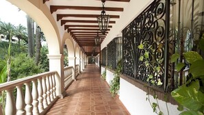 A corridor with a tiled floor, white balustrades, and a wrought iron railing with greenery. - Hotel Apartamentos Bajondillo (Torremolinos)