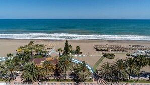 A beach view with palm trees, beach umbrellas, and a clear blue sky. - Hotel Apartamentos Bajondillo (Torremolinos)