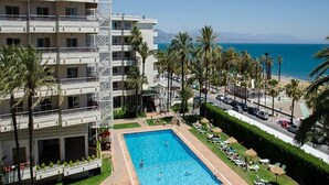 A hotel with a swimming pool, palm trees, and a view of the sea. - Hotel Apartamentos Bajondillo (Torremolinos)