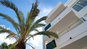 A modern building with a white facade, large windows, and a visible balcony. - Apartamentos Costamar 2 (Formentera)