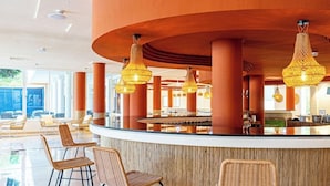 A modern lobby with a central bar area, wicker chairs, and hanging pendant lights. - Intelier Rosella Hotel (Sant Llorenc des Cardassar)