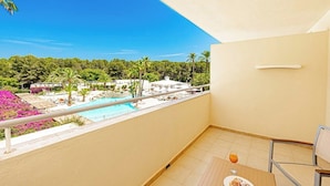 A balcony with a pool view, a glass of orange juice, and a chair. - Intelier Rosella Hotel (Sant Llorenc des Cardassar)