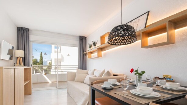 A modern hotel room with a balcony, a dining area, and a living space.