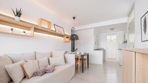 A modern living room with a sofa, a dining table, and a kitchen in the background.