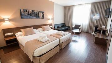 Habitació d'hotel amb llit doble, escriptori, cadira, televisió i un quadre a la paret.