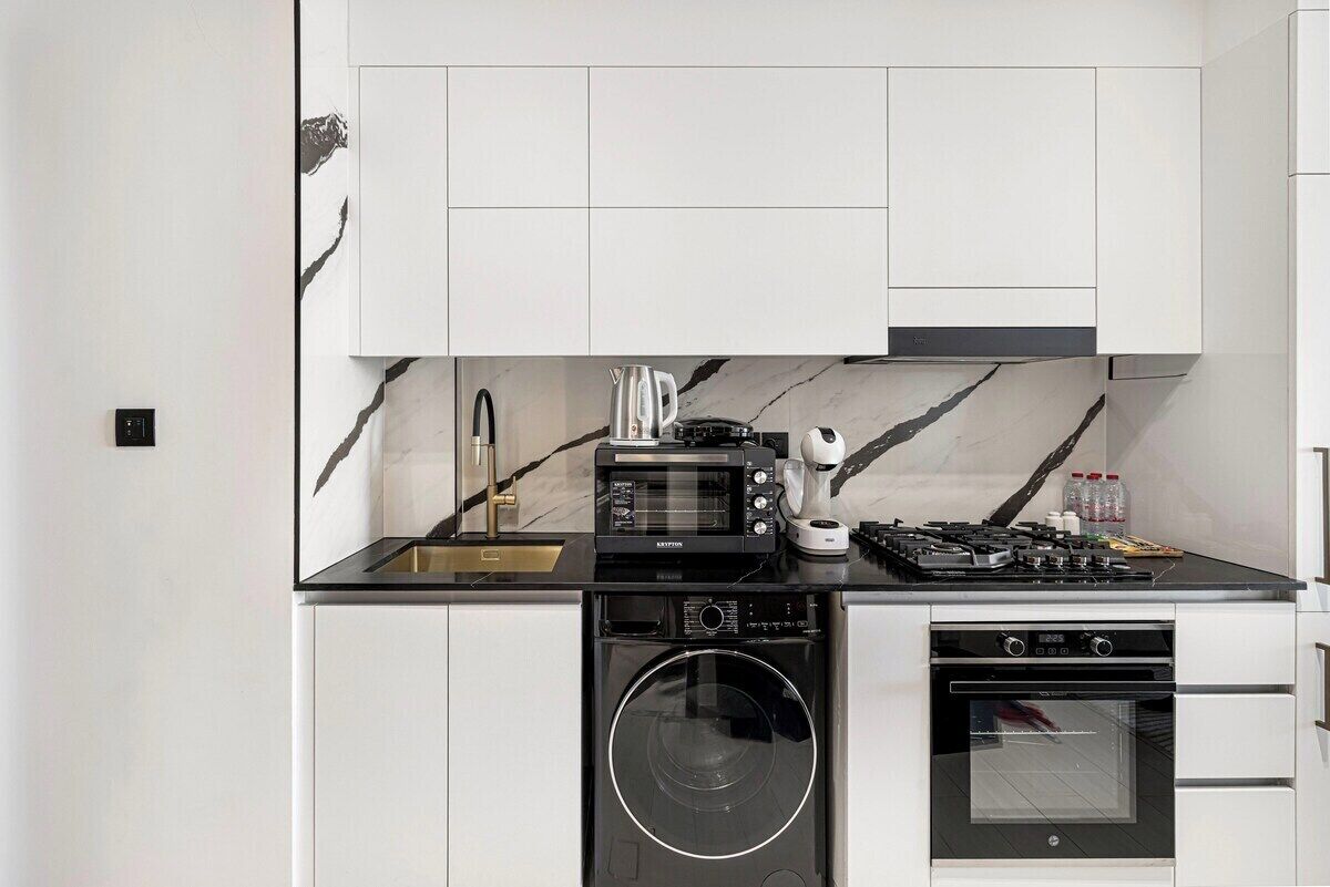 A compact kitchen with a built-in microwave, stove, oven, and washing machine.