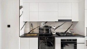 Une cuisine compacte équipée d’un four à micro-ondes, d’une cuisinière, d’un four et d’un lave-linge.