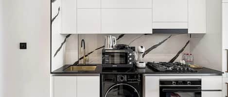 Une cuisine compacte équipée d’un four à micro-ondes, d’une cuisinière, d’un four et d’un lave-linge.