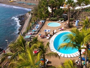 Un complexe hôtelier doté d’une grande piscine, de chaises longues et offrant une vue sur la plage.