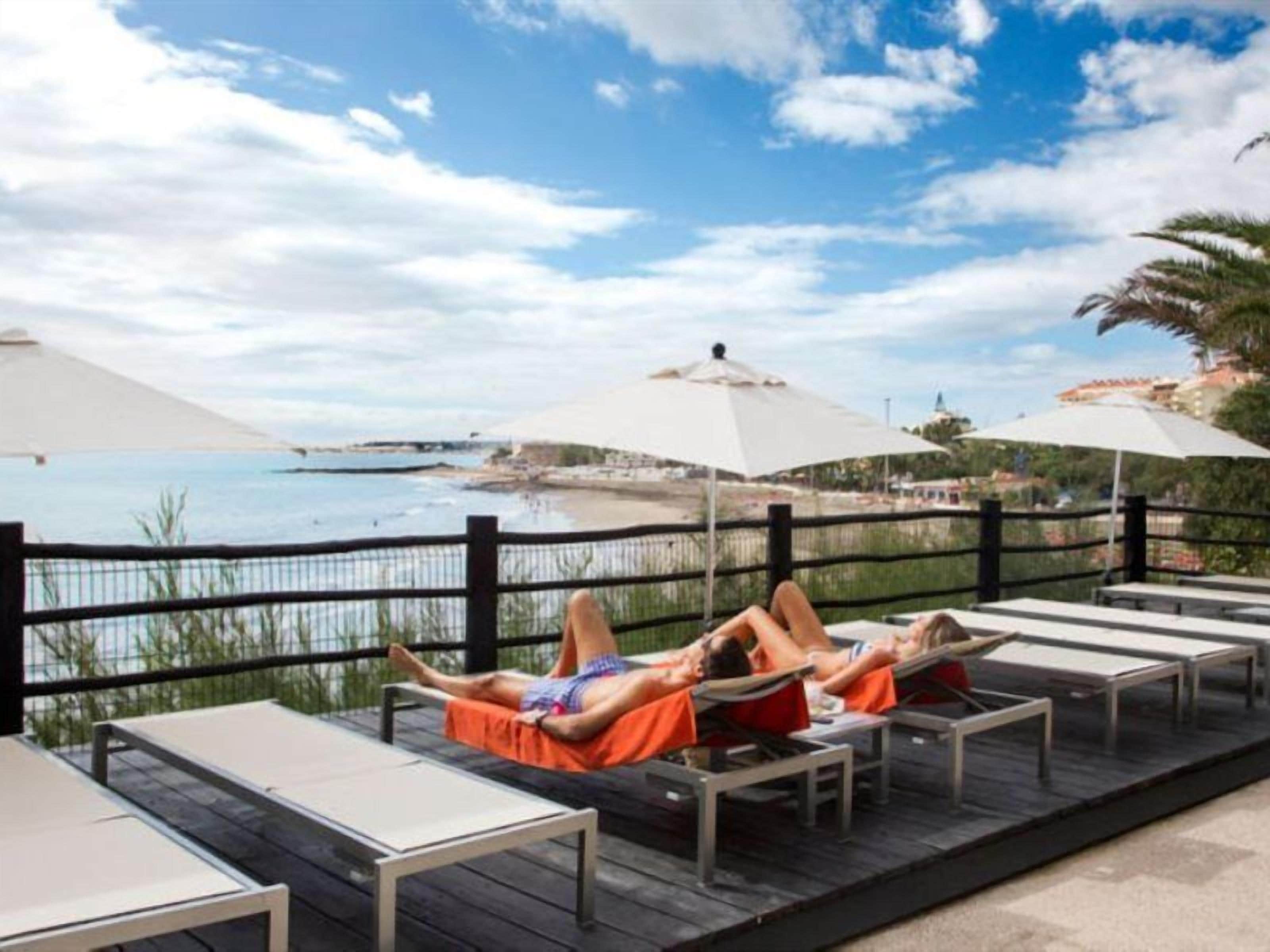 Una terraza con sillas y sombrillas frente a una playa.