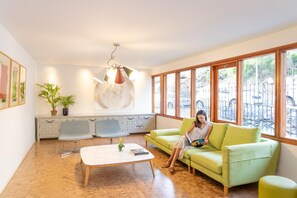 A spacious living room with a green sofa, a coffee table, and a large window with a view of an outdoor area. - Buganvillas Apartments (San Bartolomé de Tirajana)