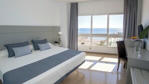 Habitación de hotel con una cama grande, un escritorio, una silla y vistas al mar.