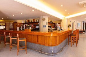 Un área de bar con muebles de madera, una barra y diversas botellas.