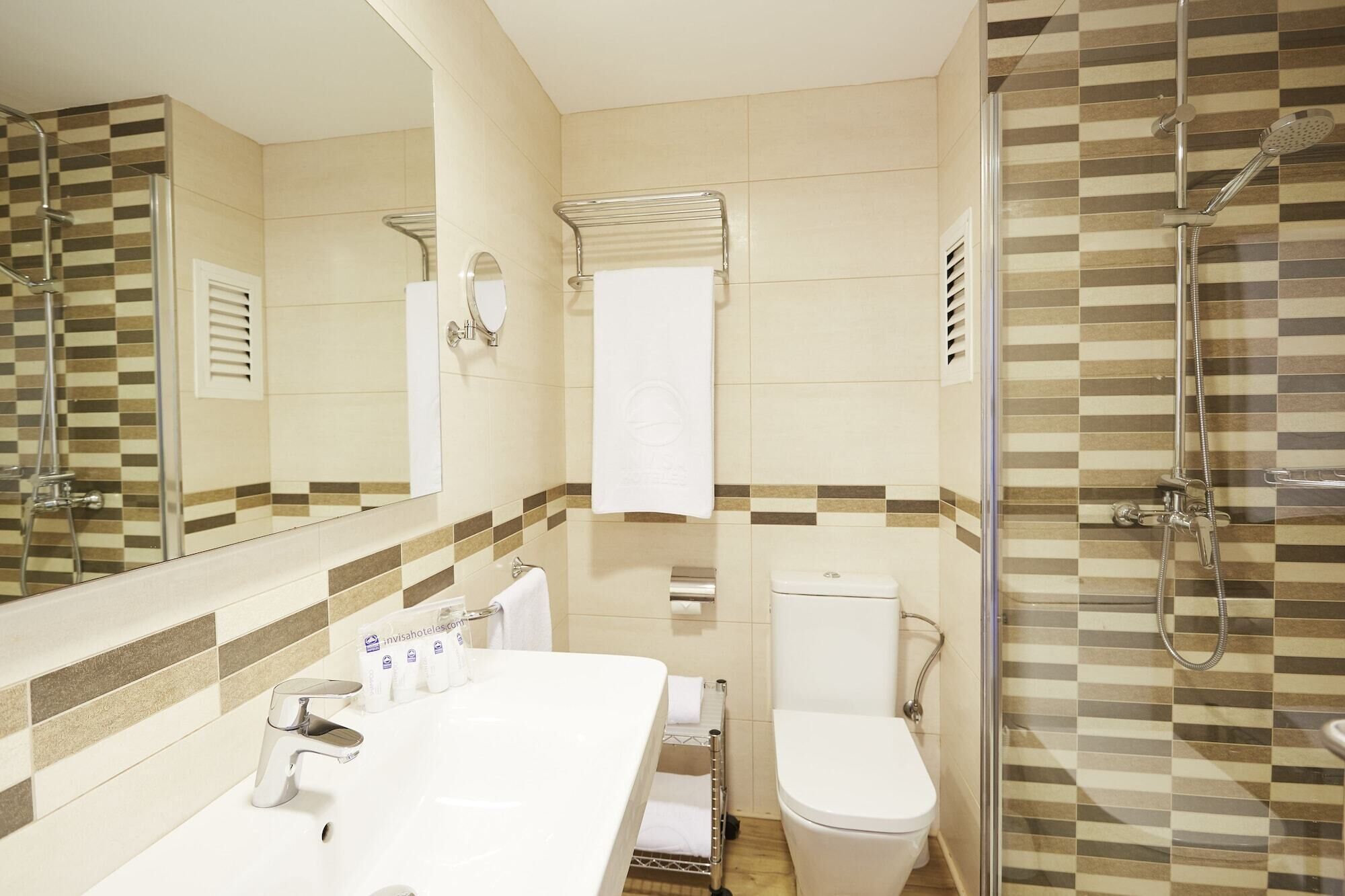 Un baño moderno con un espejo grande, un lavabo blanco, un inodoro y zona de ducha.