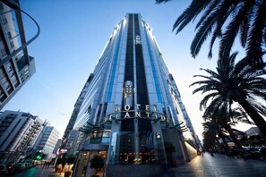 Un hôtel moderne à l’architecture verticale remarquable, avec une grande enseigne à l’entrée.