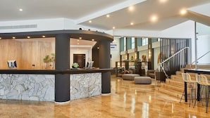 Eine moderne Lobby mit einer Rezeption, einer Treppe und einer Sitzecke.