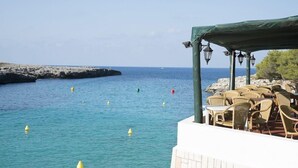 Une terrasse en bord de mer avec des sièges extérieurs et une vue sur la mer.