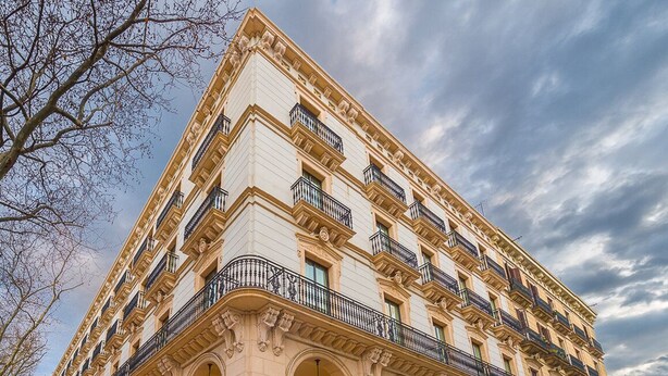 A multi-story building with a classical architectural style, featuring a series of balconies and arched doorways. - Miiro Borneta (Barcelona)