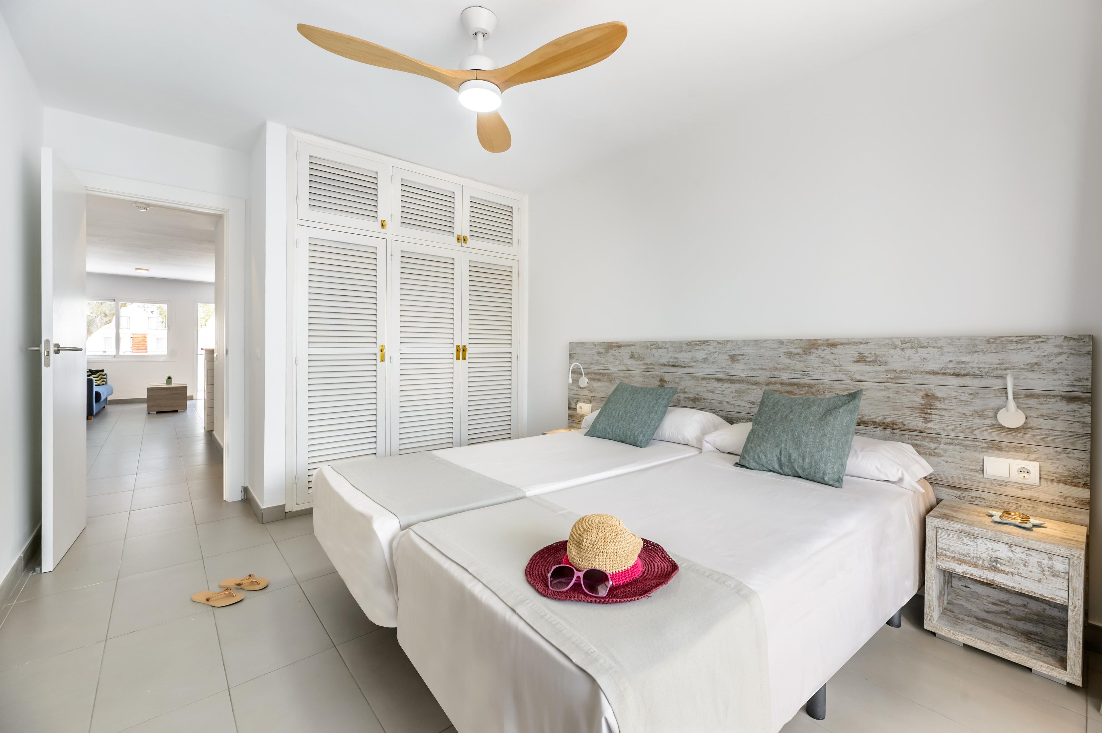 Un dormitorio con cama, mesita de noche y ventilador de techo.