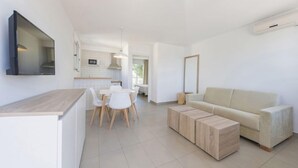 Un salon moderne et minimaliste, comprenant un canapé, une table basse et un coin repas avec des chaises et une table.