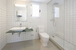 A modern bathroom with a white sink, toilet, and shower. - Vibra Riviera Apartments (Sant Josep de sa Talaia)