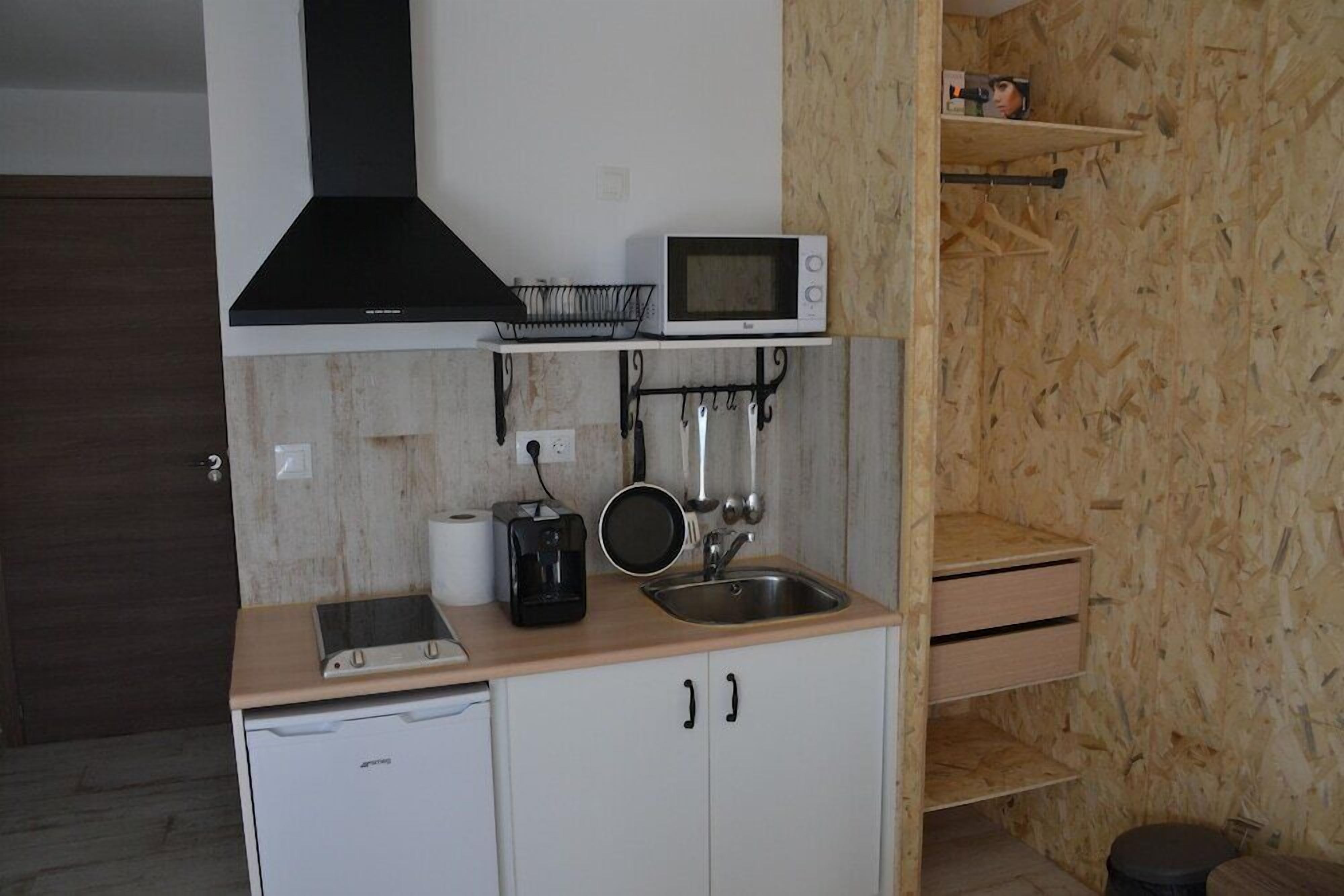 Una cocina compacta con microondas, cafetera y pileta.