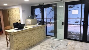 Un área de recepción con mostrador de mármol, una computadora y un letrero que indica 'SALIDA'.