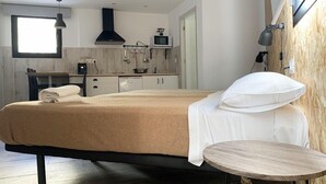 Un dormitorio moderno con cama, mesita de noche y vistas a la cocina.