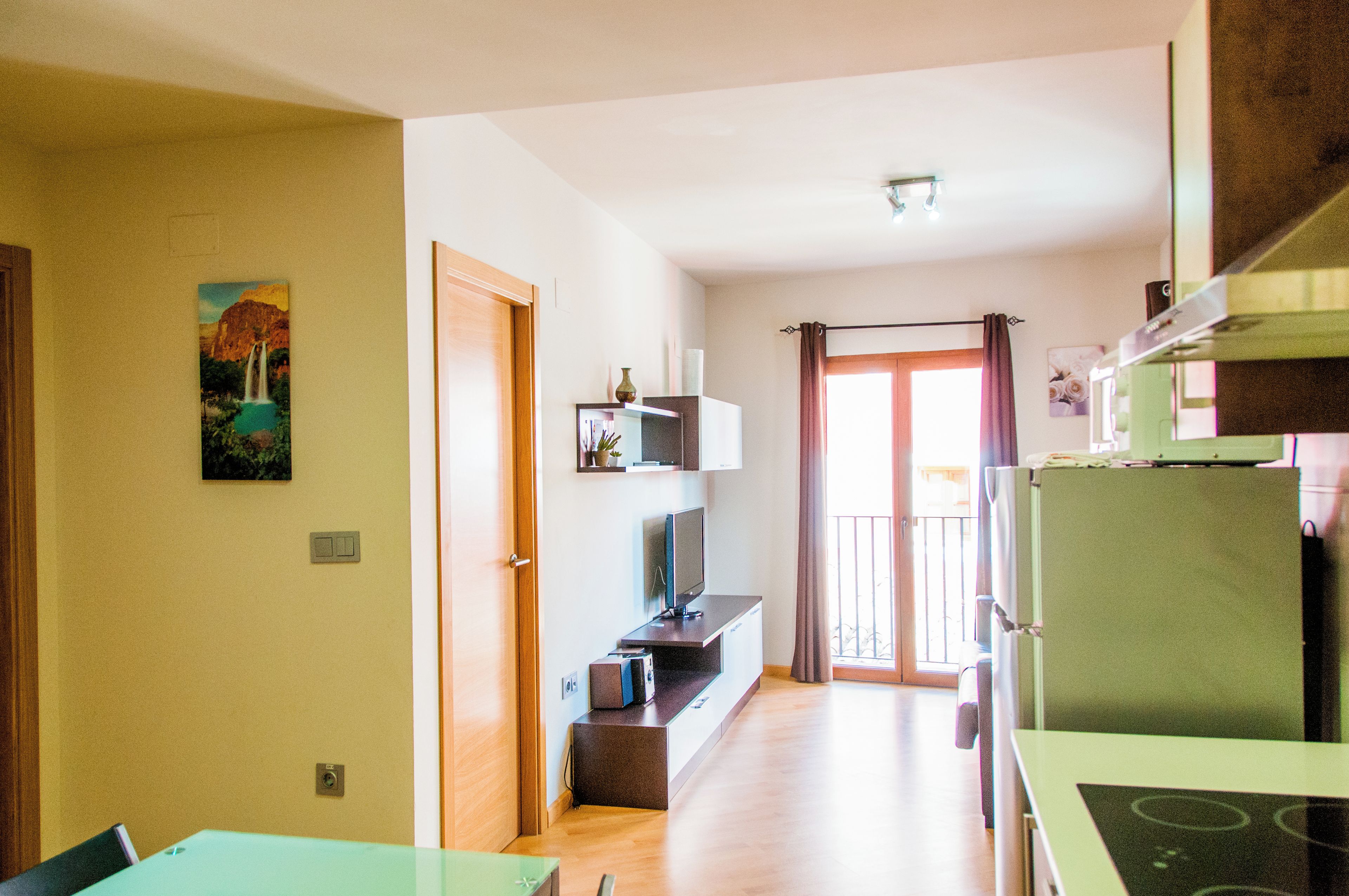 A modern kitchen with a green refrigerator, a built-in oven, and a dining area with a table and chairs.