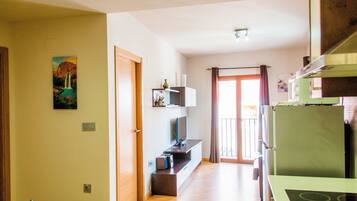 A modern kitchen with a green refrigerator, a built-in oven, and a dining area with a table and chairs.