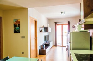 A modern kitchen with a green refrigerator, a built-in oven, and a dining area with a table and chairs. - Apartamentos Turi Sticos Costera La Mar (Villajoyosa)