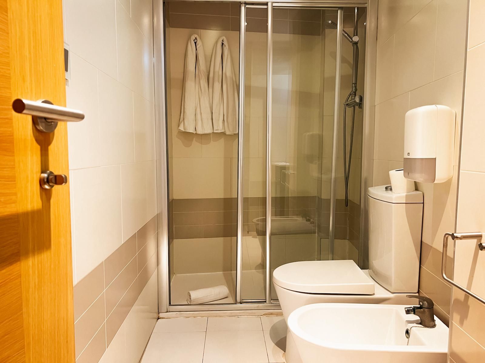A bathroom with a glass-enclosed shower, a toilet, and a sink.