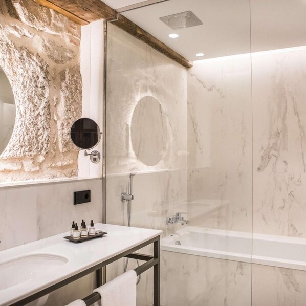 A modern bathroom with a marble vanity, a glass shower enclosure, and a large mirror. - Sofraga Palacio Hotel (Ávila)
