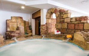 Uma área de spa com hidromassagem, paredes de pedra e porta de madeira.